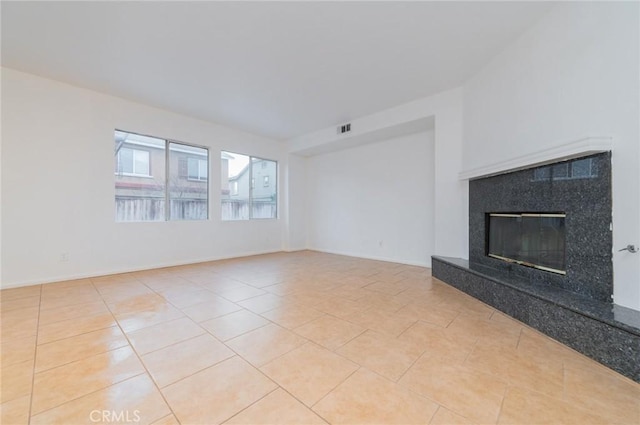 unfurnished living room with light tile patterned floors, baseboards, visible vents, and a high end fireplace