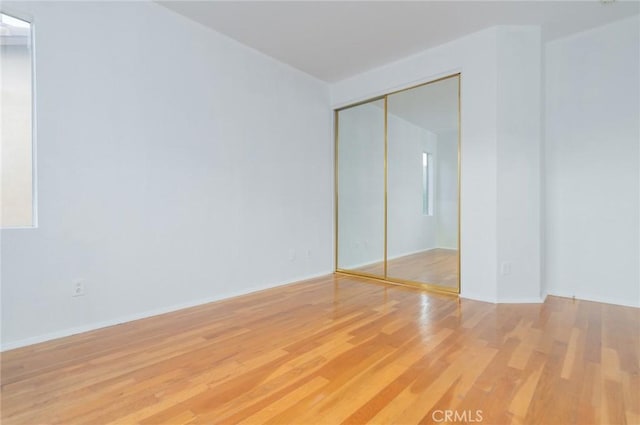 unfurnished bedroom featuring a closet and light wood-style flooring