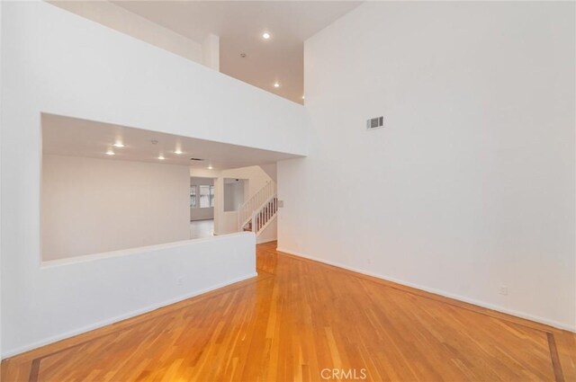 unfurnished living room with recessed lighting, wood finished floors, visible vents, baseboards, and stairs