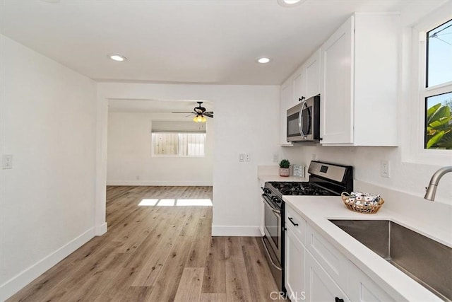 kitchen featuring stainless steel appliances, plenty of natural light, white cabinets, and a sink