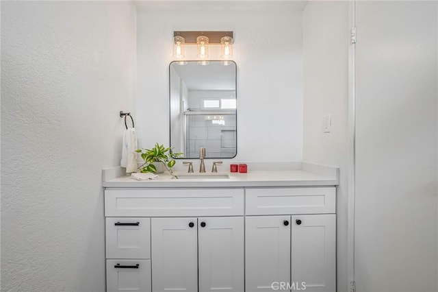 bathroom with a textured wall, a shower with door, and vanity