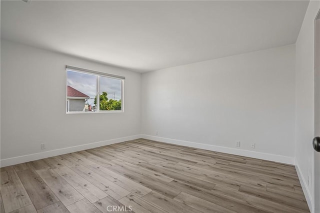 spare room with baseboards and wood finished floors