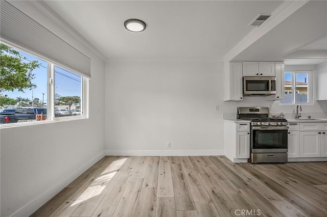 kitchen with light wood finished floors, visible vents, white cabinets, appliances with stainless steel finishes, and a sink