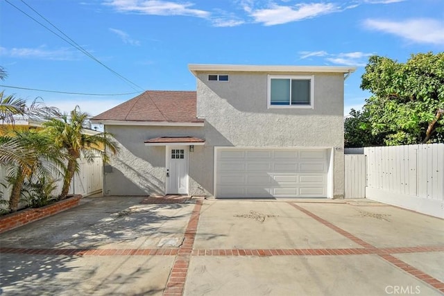 traditional-style home with driveway, fence, an attached garage, and stucco siding