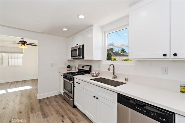 kitchen with white cabinetry, stainless steel appliances, a sink, and light countertops