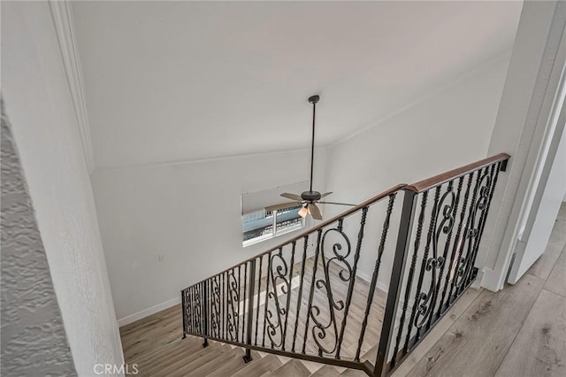 stairway with crown molding, wood finished floors, a ceiling fan, and baseboards