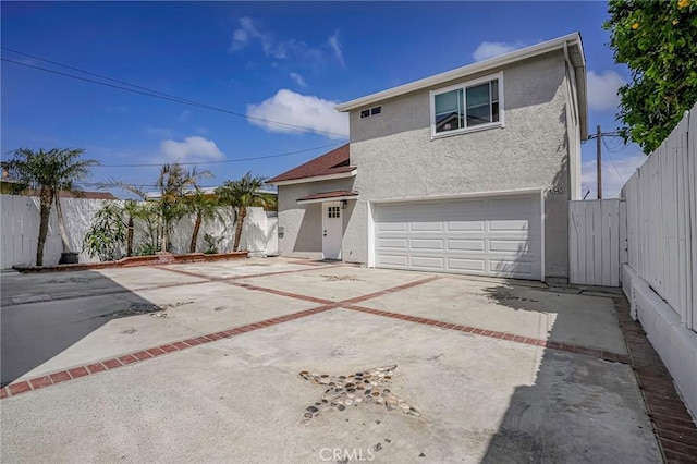 traditional-style home with a garage, driveway, fence, and stucco siding