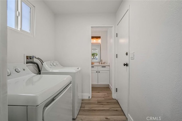 washroom featuring light wood-style flooring, laundry area, plenty of natural light, and washer and clothes dryer