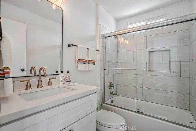 bathroom featuring enclosed tub / shower combo, vanity, and toilet