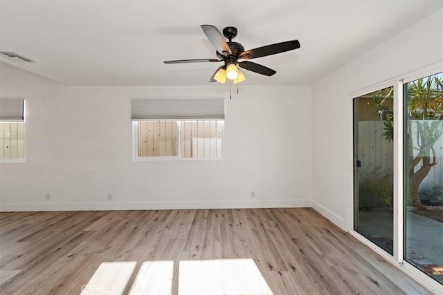 unfurnished room with a ceiling fan, visible vents, baseboards, and wood finished floors