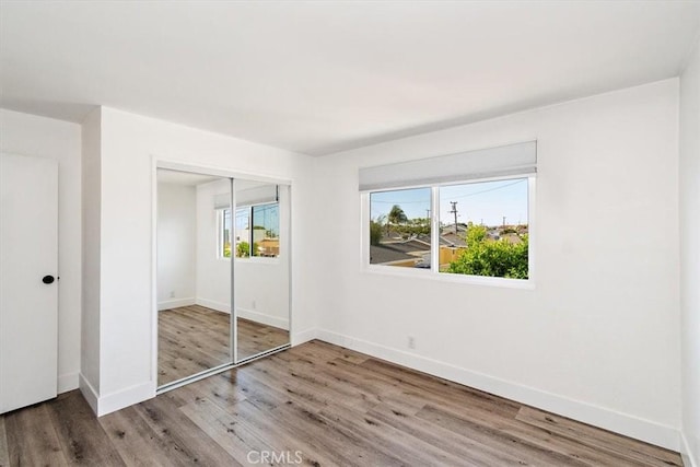 unfurnished bedroom with a closet, baseboards, and wood finished floors