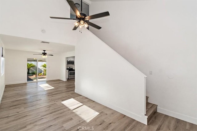 unfurnished living room with baseboards, stairs, visible vents, and wood finished floors