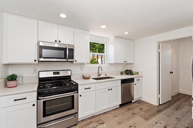 kitchen with white cabinetry, stainless steel appliances, a sink, and light countertops