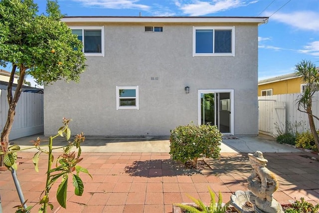 rear view of house with a patio area, a fenced backyard, and stucco siding