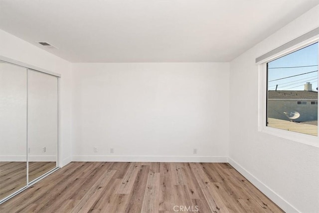 unfurnished bedroom with light wood-style floors, a closet, visible vents, and baseboards