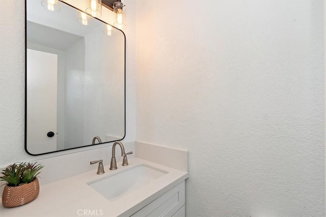 bathroom with a textured wall and vanity