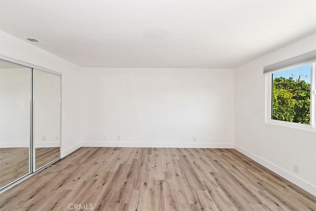 unfurnished bedroom with light wood-style flooring, a closet, visible vents, and baseboards