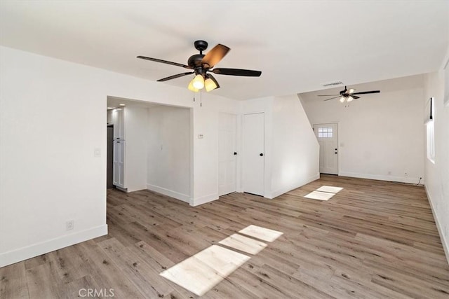 empty room with ceiling fan, wood finished floors, visible vents, and baseboards