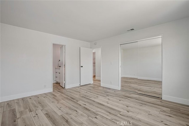 unfurnished bedroom with a closet, light wood-style flooring, and baseboards