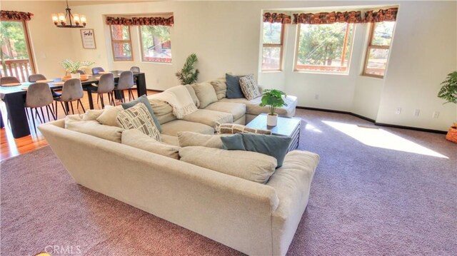 living room with a notable chandelier, baseboards, and carpet