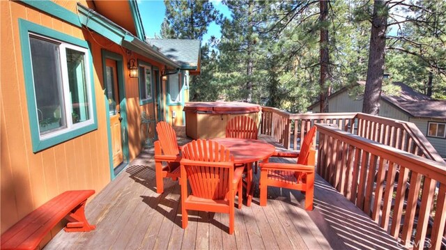 wooden deck with a hot tub and outdoor dining area