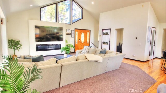 living area with a glass covered fireplace, high vaulted ceiling, wood finished floors, and recessed lighting