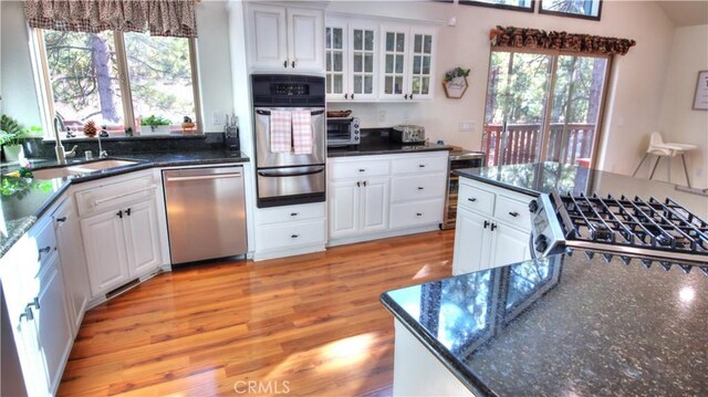 kitchen with light wood-type flooring, gas range oven, stainless steel dishwasher, a warming drawer, and a sink