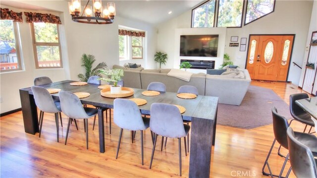 dining area featuring vaulted ceiling, a notable chandelier, and light wood-style floors