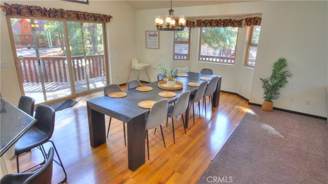 dining space featuring light wood-style floors, baseboards, and a notable chandelier