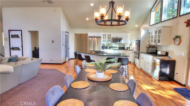 dining area with a notable chandelier, high vaulted ceiling, and light wood finished floors