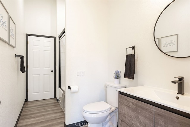 bathroom with toilet, vanity, and wood finished floors