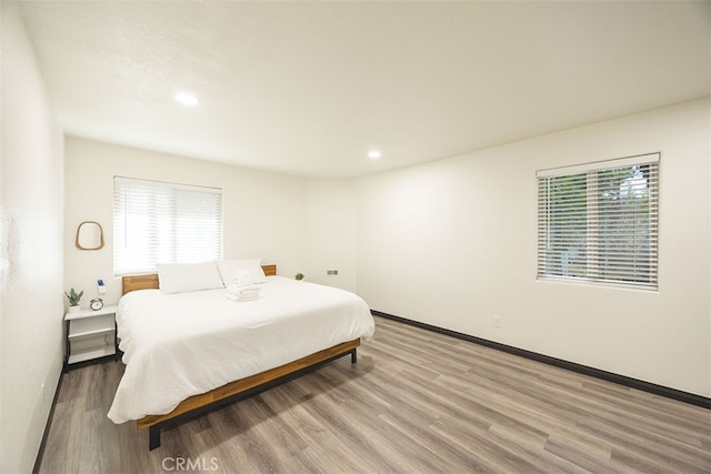 bedroom featuring wood finished floors, recessed lighting, and baseboards