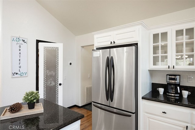 kitchen with freestanding refrigerator, vaulted ceiling, white cabinets, dark wood-style floors, and dark stone counters