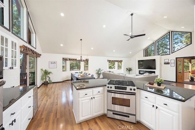 kitchen with gas stove, high vaulted ceiling, plenty of natural light, dark stone countertops, and recessed lighting
