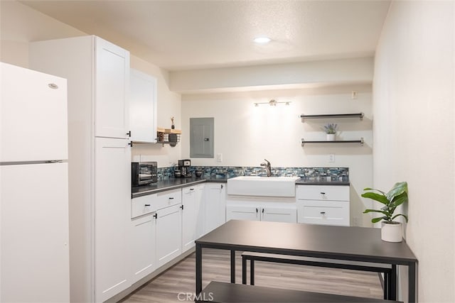 kitchen with freestanding refrigerator, a sink, dark countertops, white cabinets, and recessed lighting