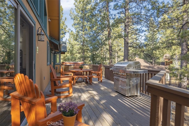 wooden deck with outdoor dining space, a jacuzzi, and view of scattered trees