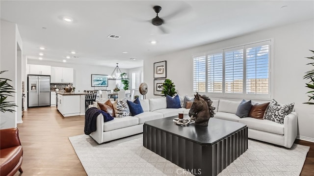 living room featuring a ceiling fan, recessed lighting, visible vents, and light wood-style floors