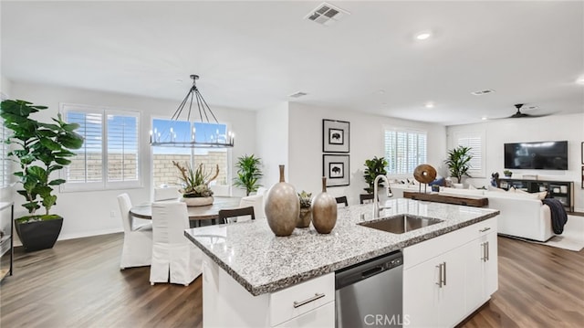 kitchen featuring dark wood-style flooring, a sink, open floor plan, stainless steel dishwasher, and light stone countertops