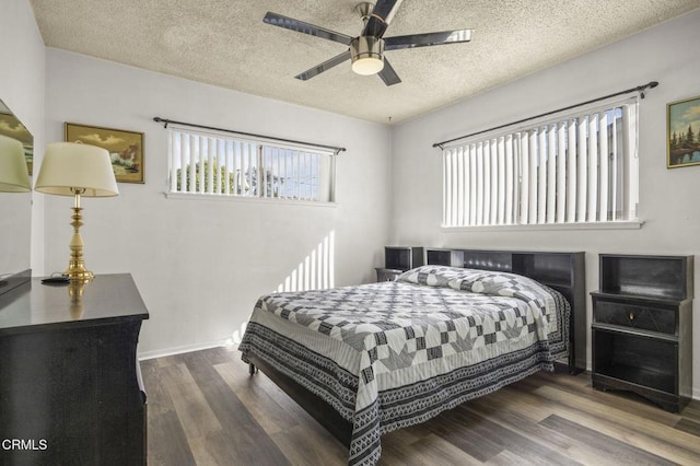 bedroom with a ceiling fan, a textured ceiling, baseboards, and wood finished floors