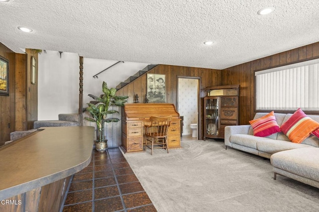living room featuring recessed lighting, a textured ceiling, wood walls, and stairway