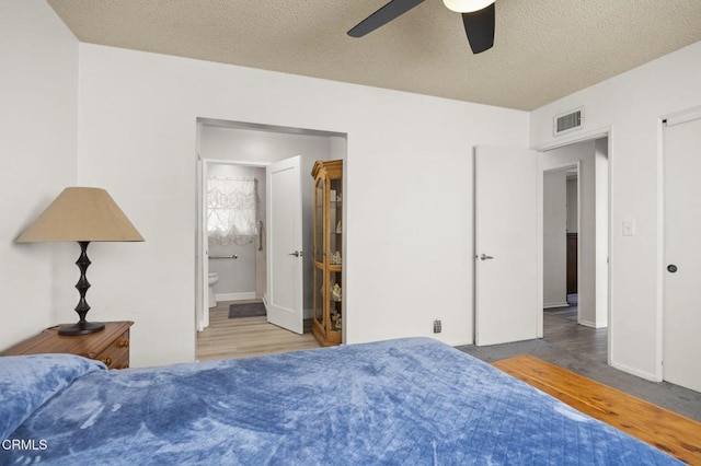 bedroom featuring visible vents, a ceiling fan, wood finished floors, and a textured ceiling