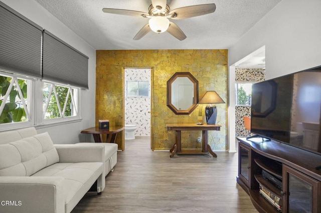 living room with wood finished floors, ceiling fan, and a textured ceiling