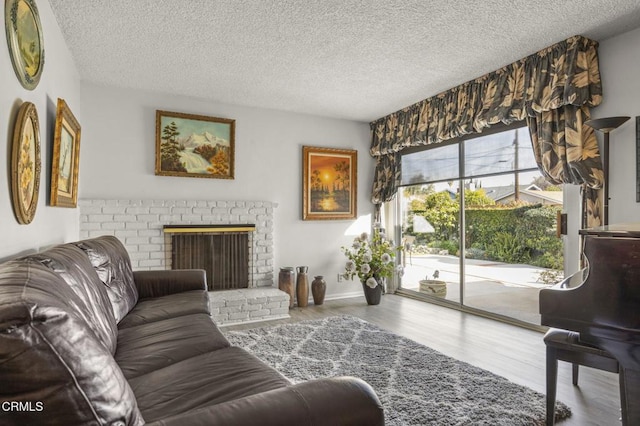 living area featuring a brick fireplace, a textured ceiling, and wood finished floors
