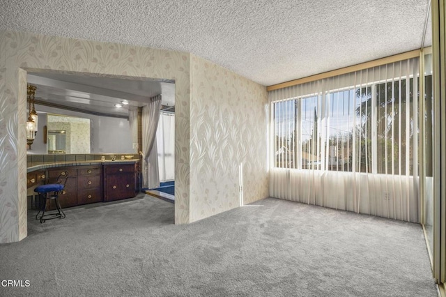 interior space featuring wallpapered walls, carpet, and a textured ceiling