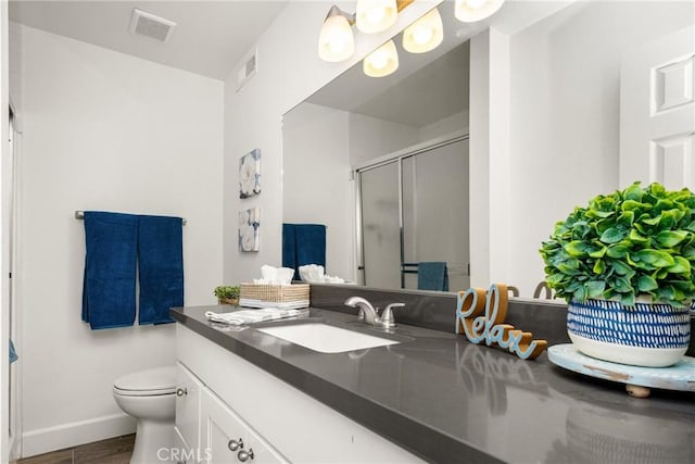 full bath with visible vents, vanity, a shower stall, and toilet