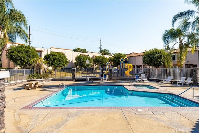 community pool featuring playground community, a patio area, a community hot tub, and fence