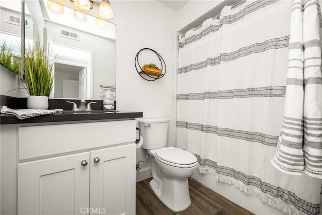 full bath with visible vents, toilet, wood finished floors, and vanity