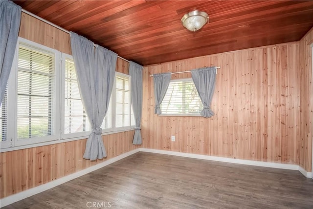 empty room featuring wood ceiling, wood walls, baseboards, and wood finished floors