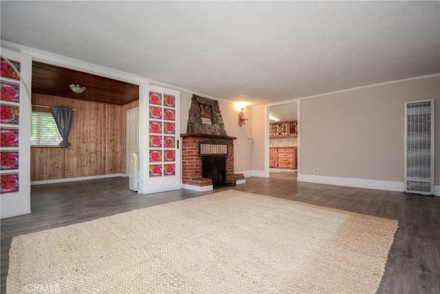 unfurnished living room featuring a heating unit, a brick fireplace, wood finished floors, and baseboards