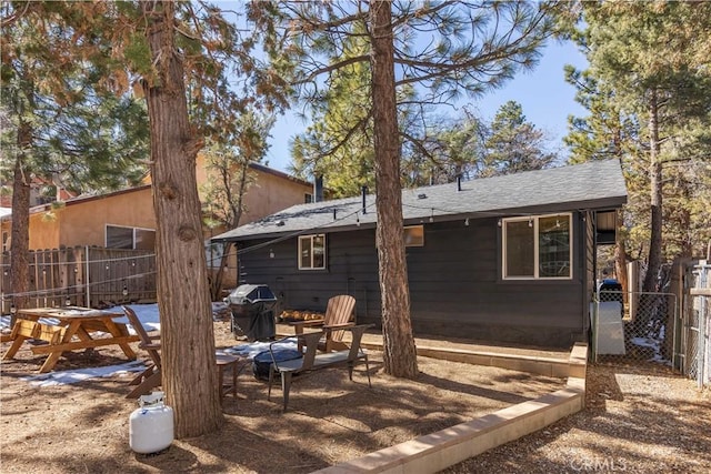 rear view of property featuring a shingled roof, fence, and a patio